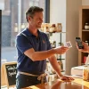 Male shop owner in real work clothes giving customer a QR code review card